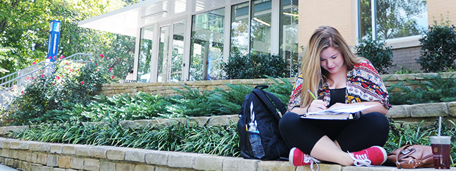 Student siting on a bench writing