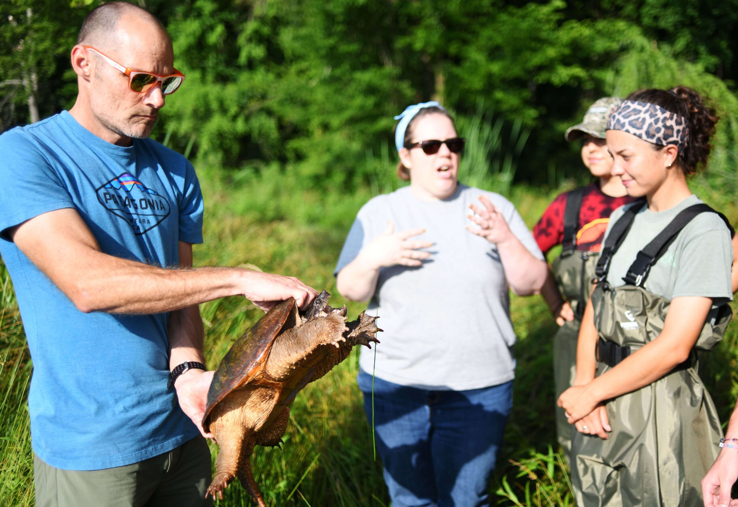Man holds a turtle as students learn about him
