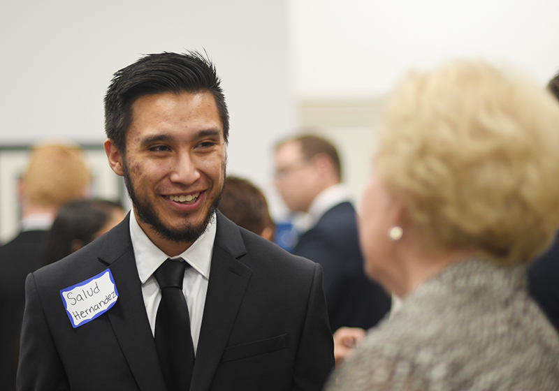 Gentleman with name tag smiling at older woman at function