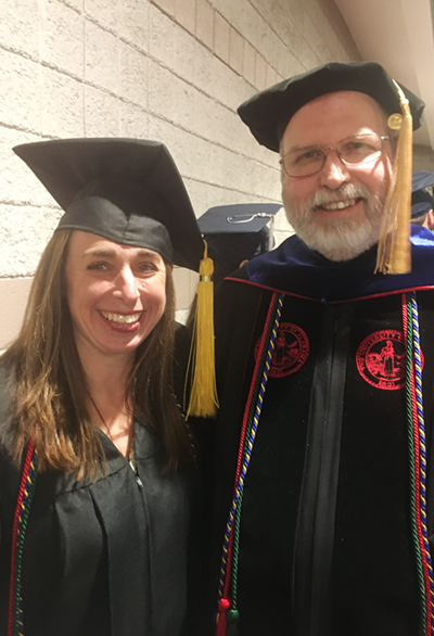 Professor with student wearing graduation robes