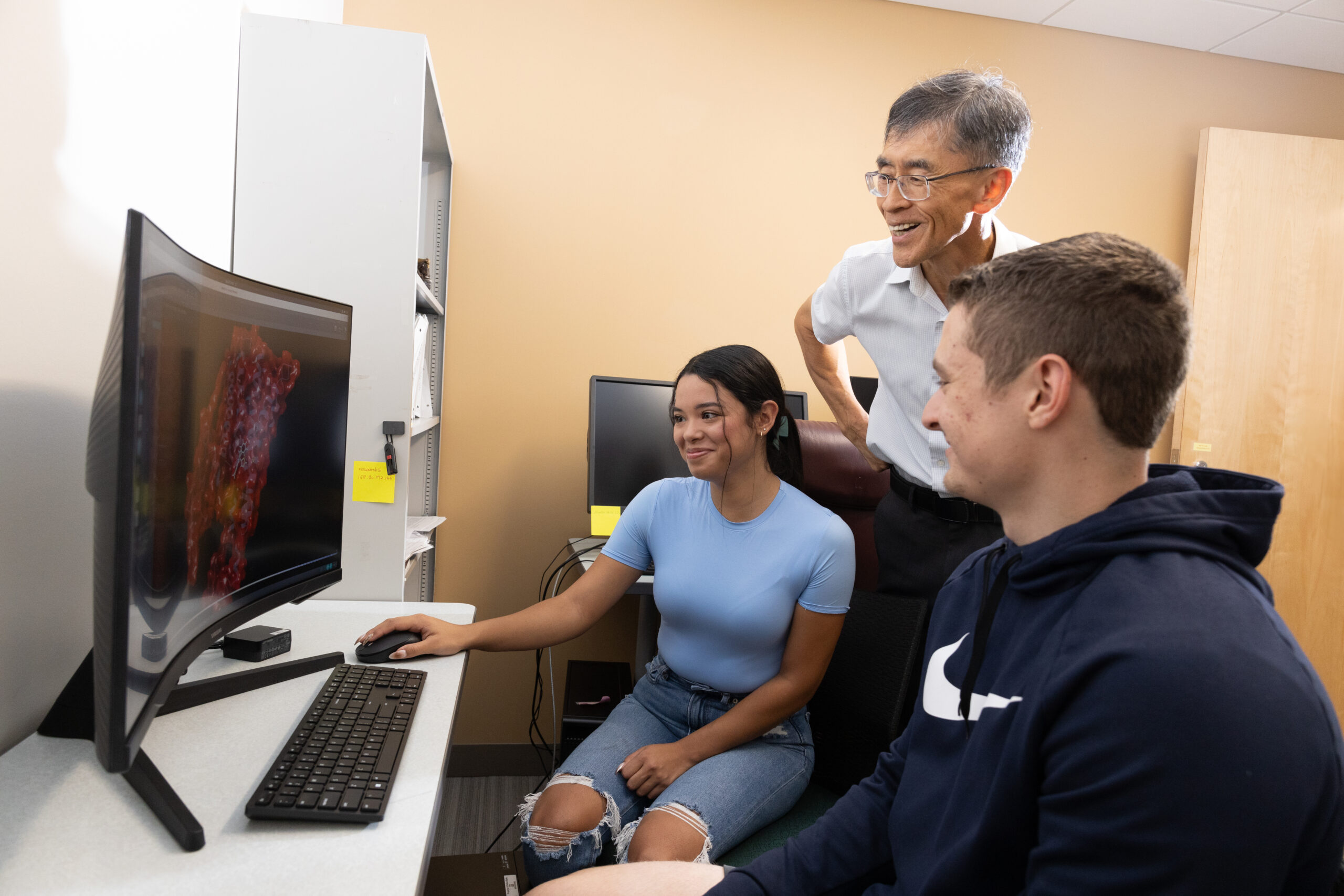 Students and faculty observing a computer monitor together