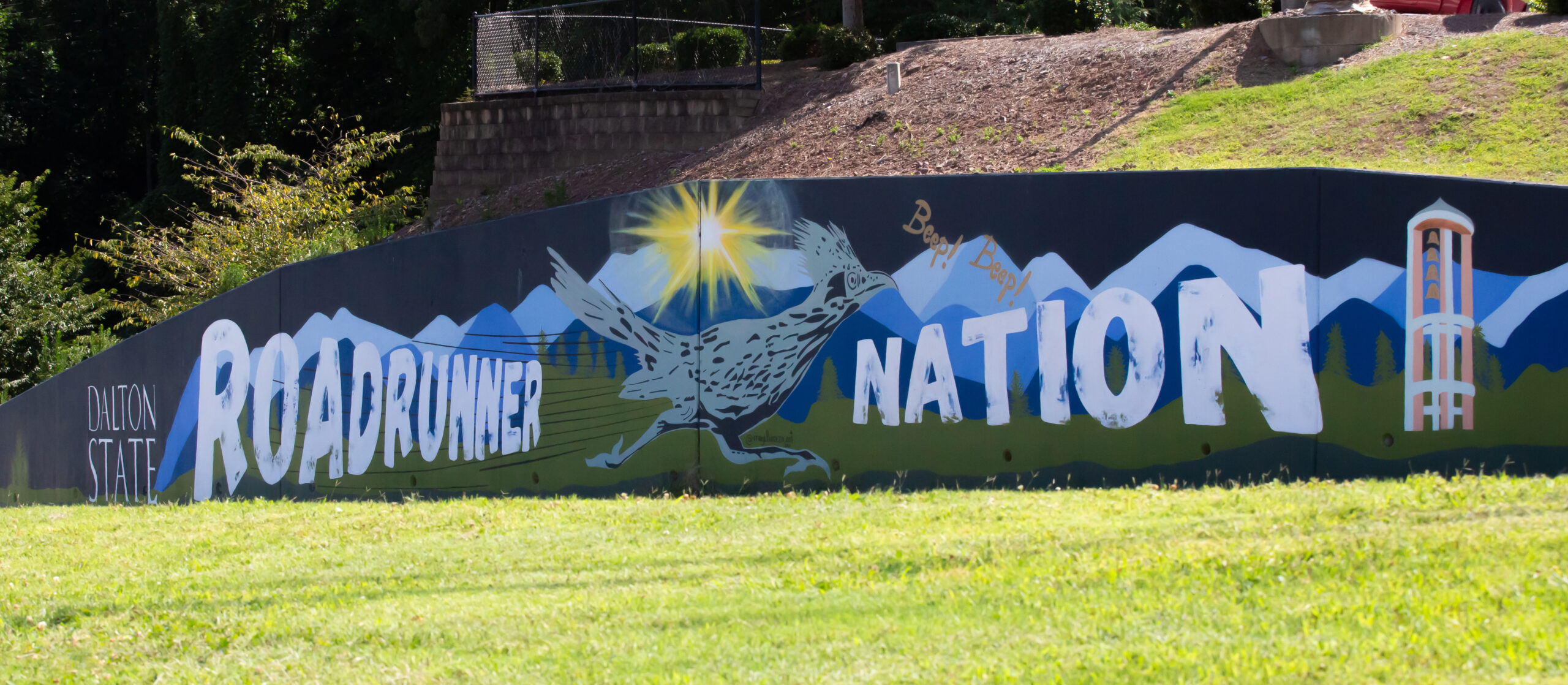 A mural depicting a sweeping view of the north Georgia mountains, Dalton State’s iconic bell tower, a life-like Roadrunner—the college’s official mascot—and the words “Roadrunner Nation” set against a radiant sunrise.