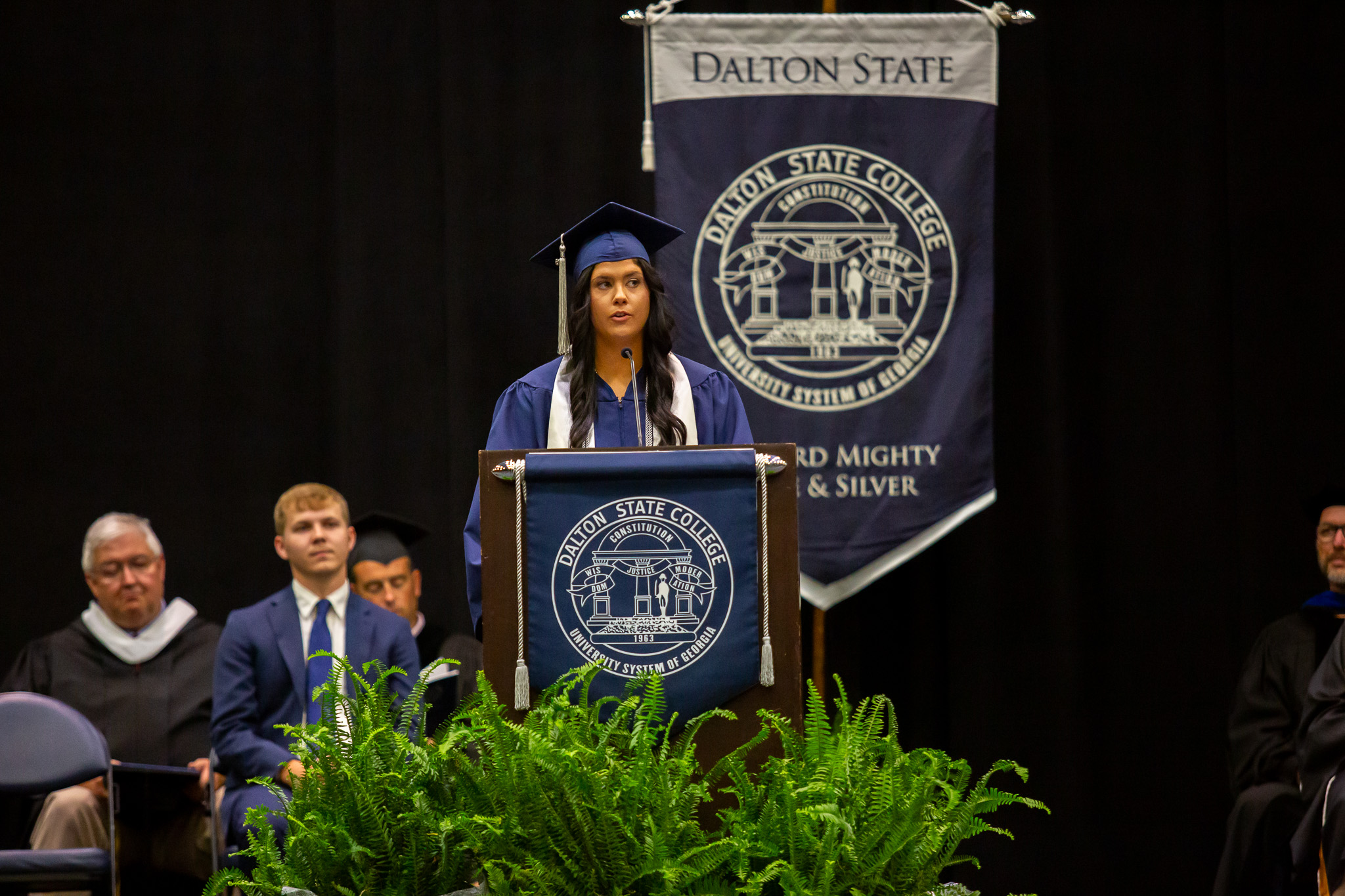 A female graduate speaks at a commencement ceremony.