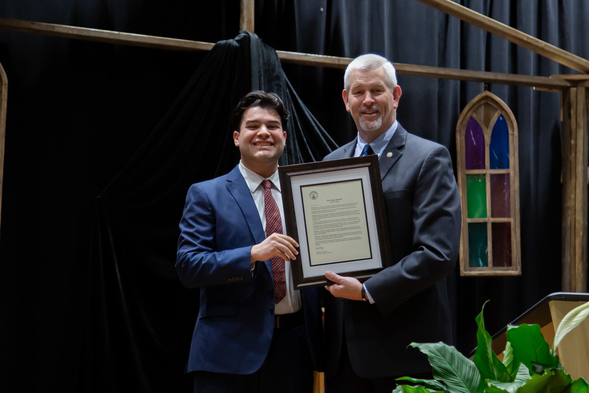 A man presents a Dalton State student with a framed honors recognition.